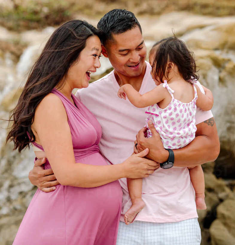 ecstatic-pregnant-asian-wife-and-husband-holding-young-daughter-cavf92781.jpeg